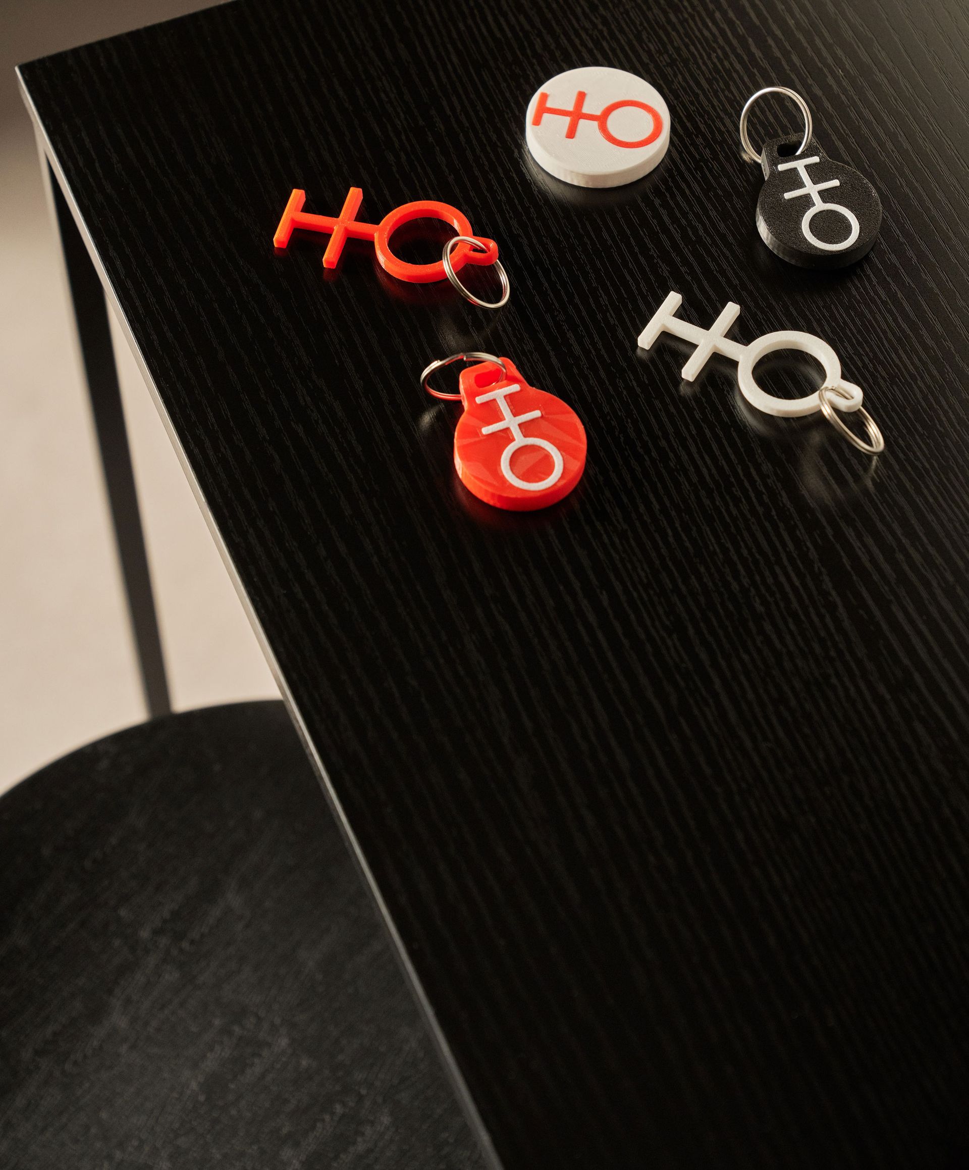 Portachiavi e bottone con logo rosso e bianco su superficie nera.