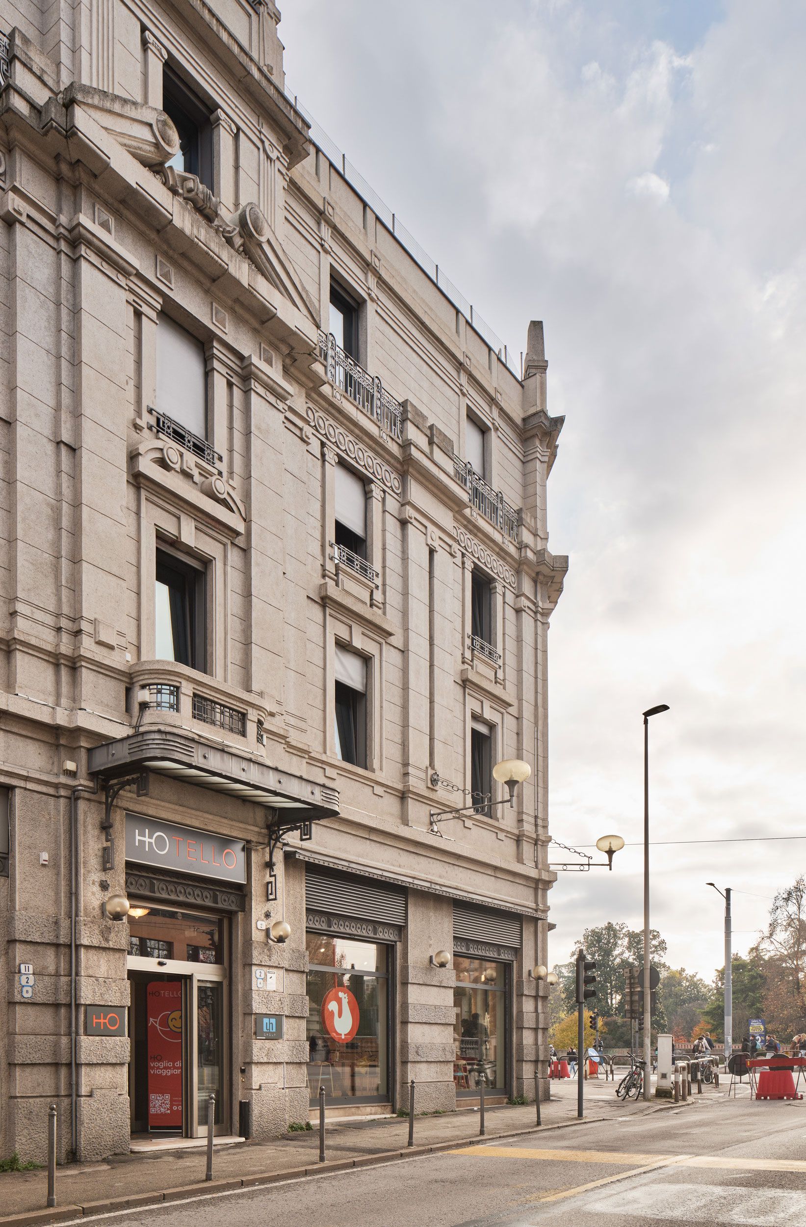 Vista d'angolo di un edificio in pietra chiara su una strada cittadina; piani superiori con finestre e piccoli balconi.