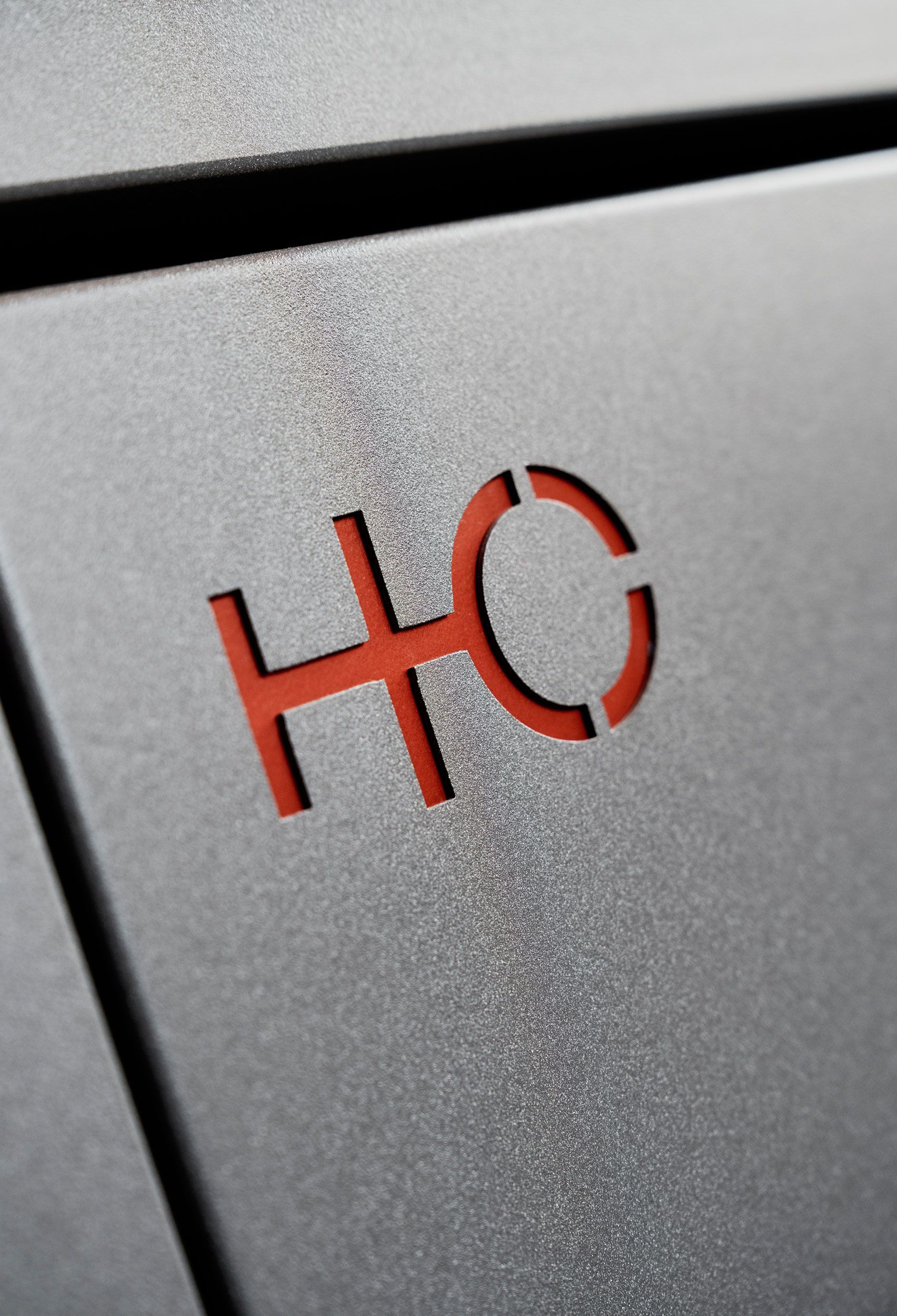Logo HO rosso su una superficie grigia testurizzata.