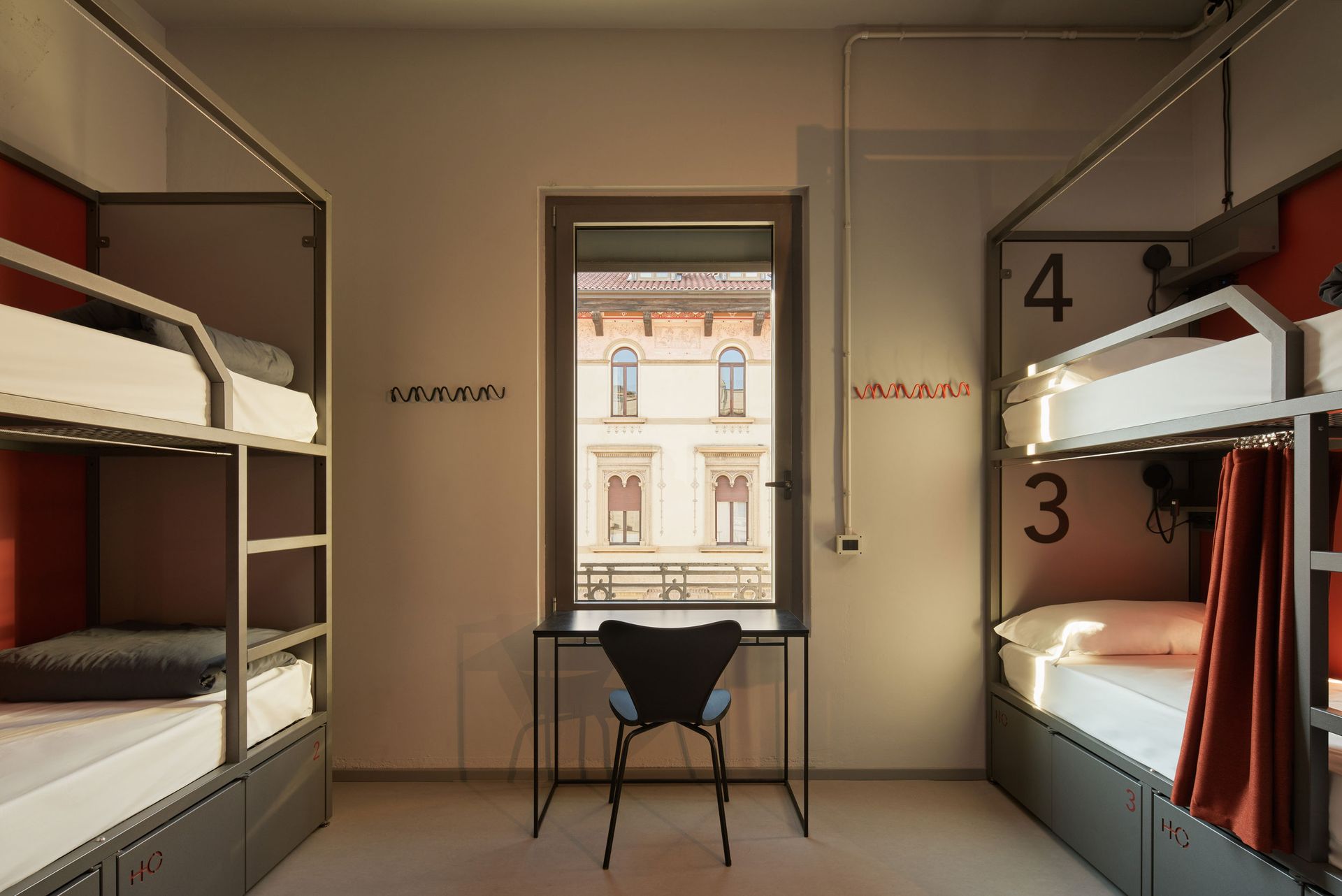 Camera in ostello con due letti a castello e una scrivania vicino alla finestra.