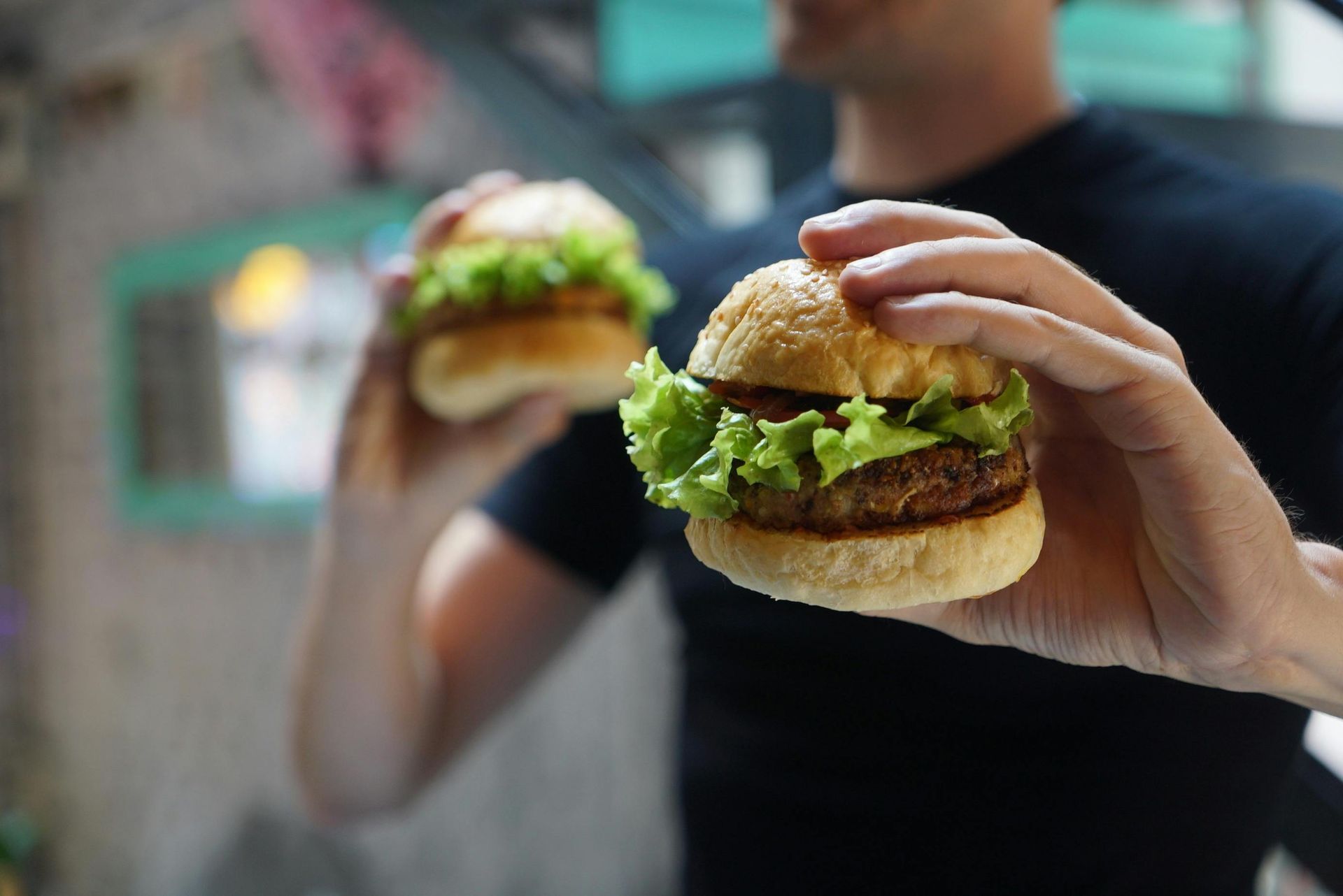 Un uomo tiene due hamburger nelle sue mani.