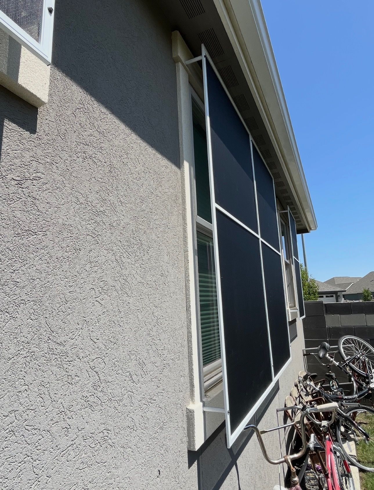 Side view of a house with a screened porch, white trim, and bicycles lined up along the wall.