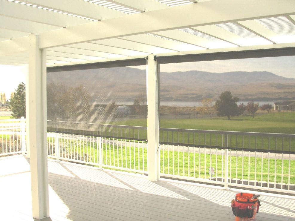 Covered porch overlooking a green field and mountains, with a red toolbox on the floor.