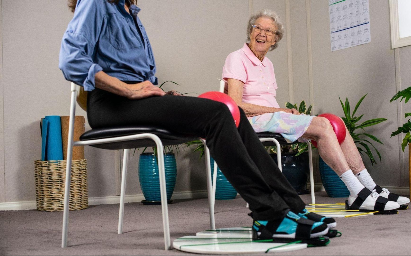 a man and a woman are sitting in chairs with exercise balls .