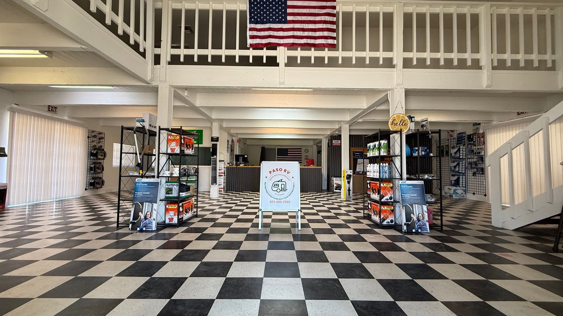 Spacious shop interior with black-and-white checkered floor, display shelves, and a large American flag overhead