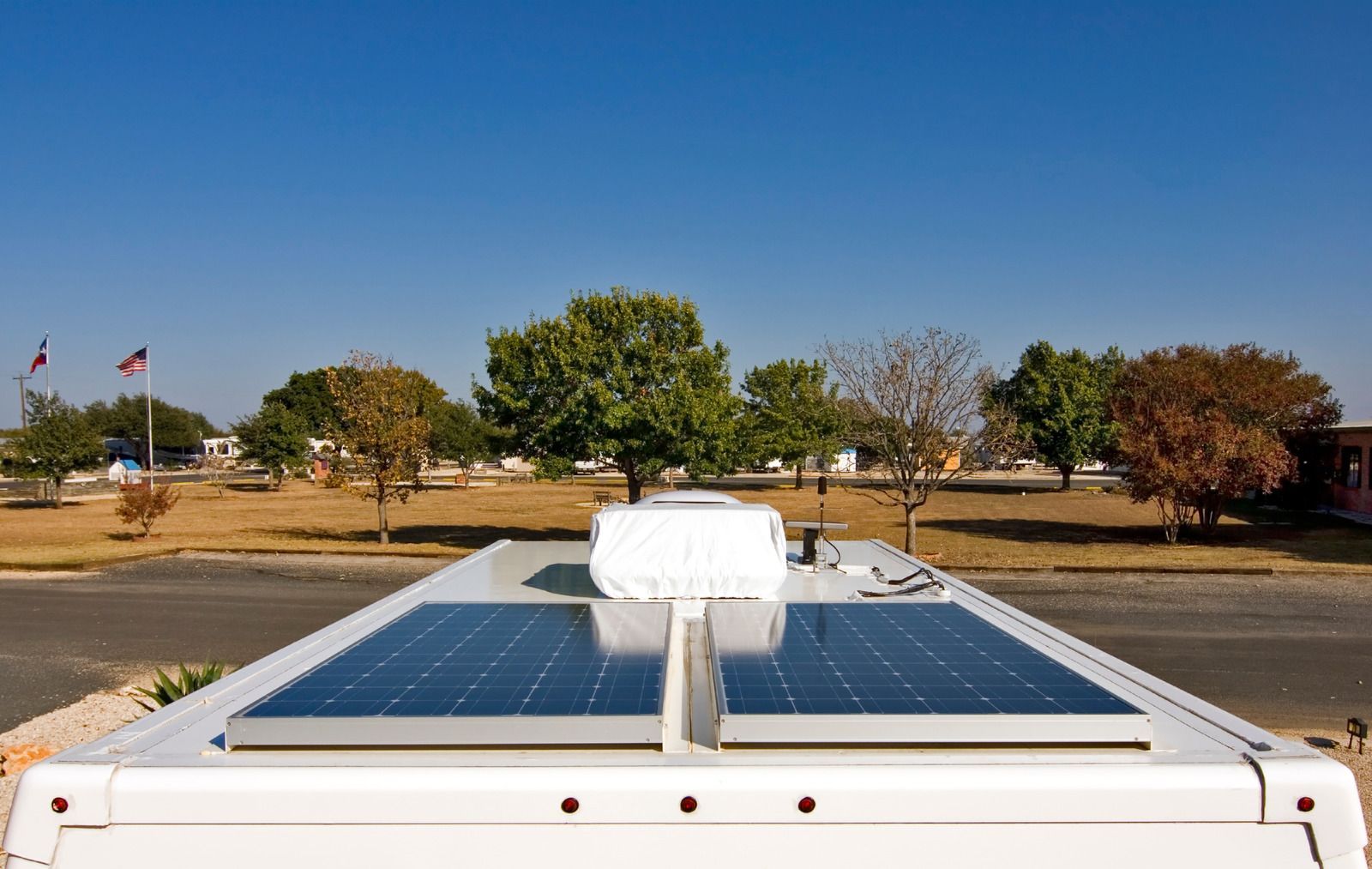 Worker in hard hat inspecting solar panels outdoors at sunset