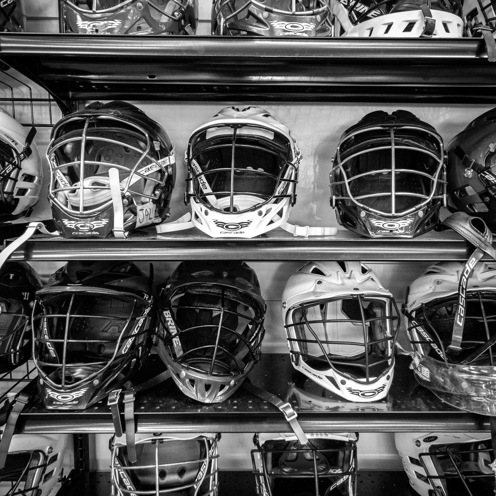 Rows of hockey goalie helmets with metal face cages stacked on shelves in a sports gear store