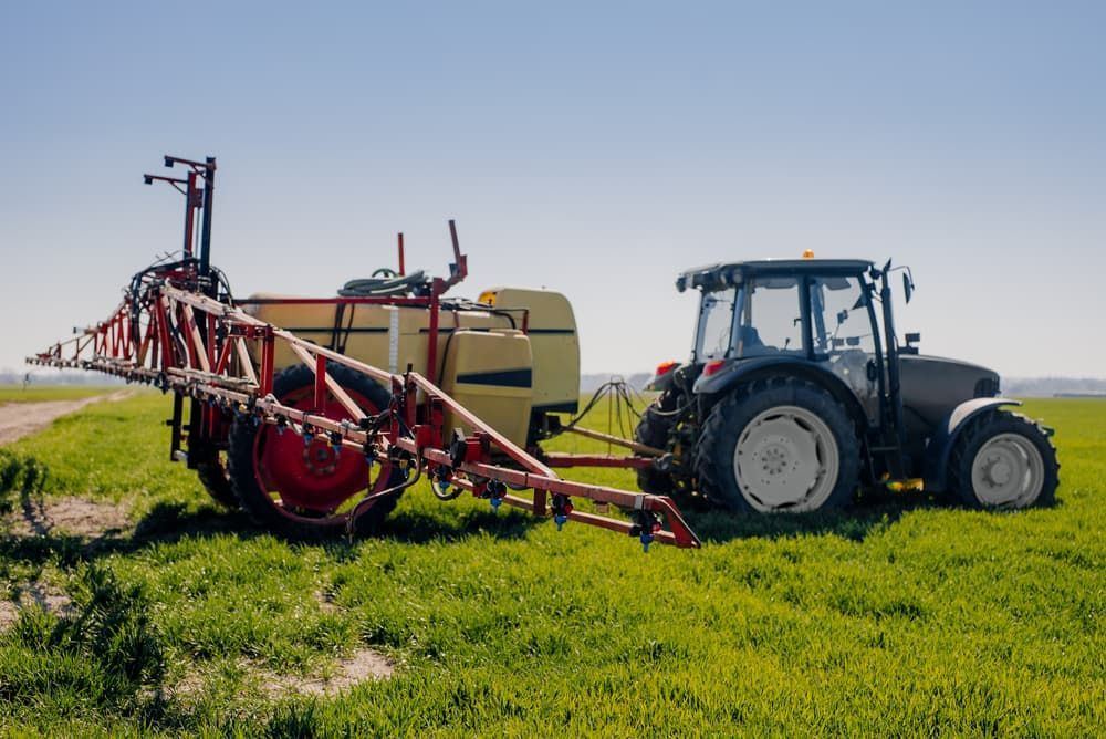 A Tractor Is Spraying a Field with A Sprayer Attached to It — Thompson's Farm Gear In Wauchope, NSW