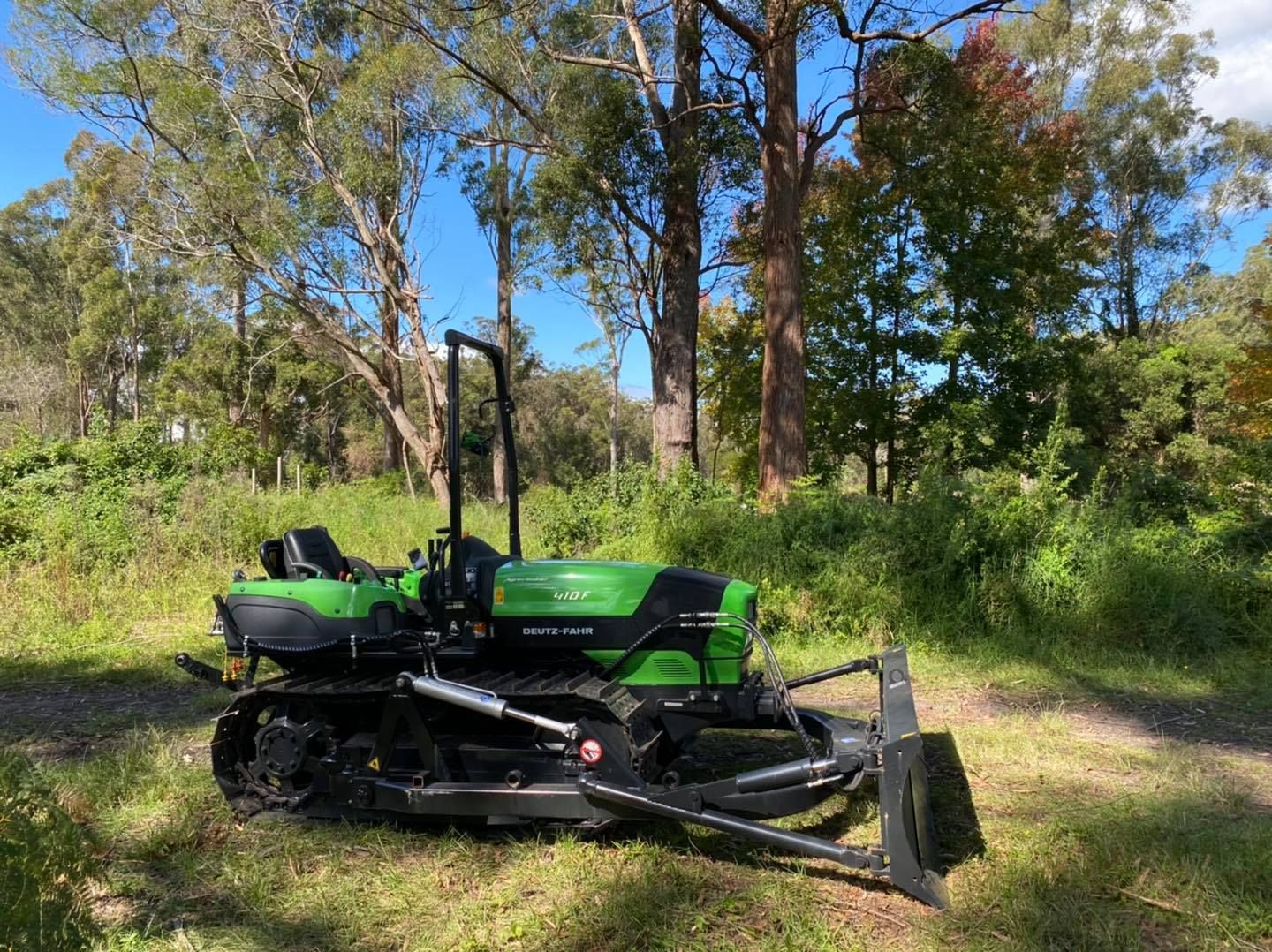 A Red Tractor Is Plowing a Field with A Plow — Thompson's Farm Gear In Port Macquarie, NSW
