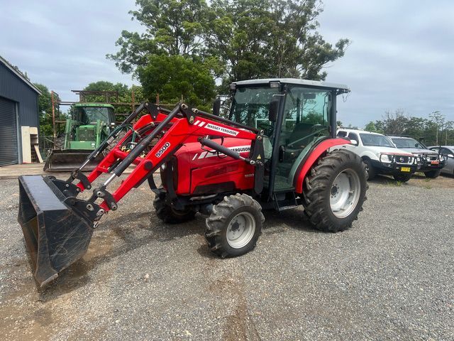 A Red Tractor With a Front Loader is Parked in a Gravel Lot — Thompson's Farm Gear In Wauchope, NSW