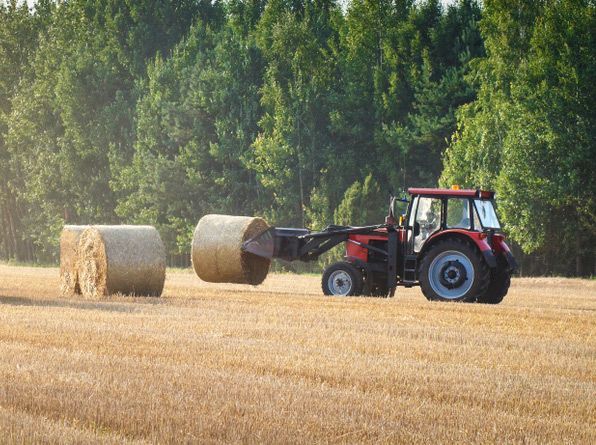 Agricultural Machinery Moving Hay Bales on a Golden Field After Grain Harvest — Thompson's Farm Gear In Wingham, NSW