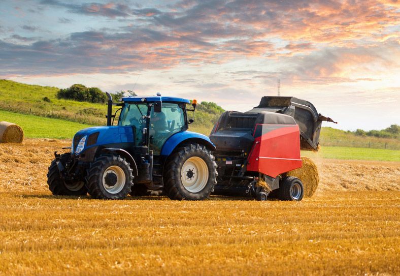 Blue Tractor with Hay Bale Machinery on the Farm — Thompson's Farm Gear In Wauchope, NSW
