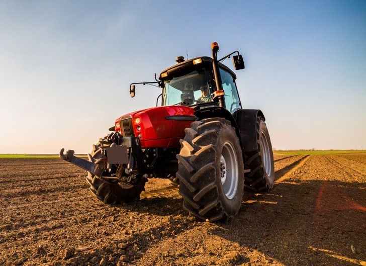 Farmer Operating Red Tractor on the Farm — Thompson's Farm Gear In Wauchope, NSW