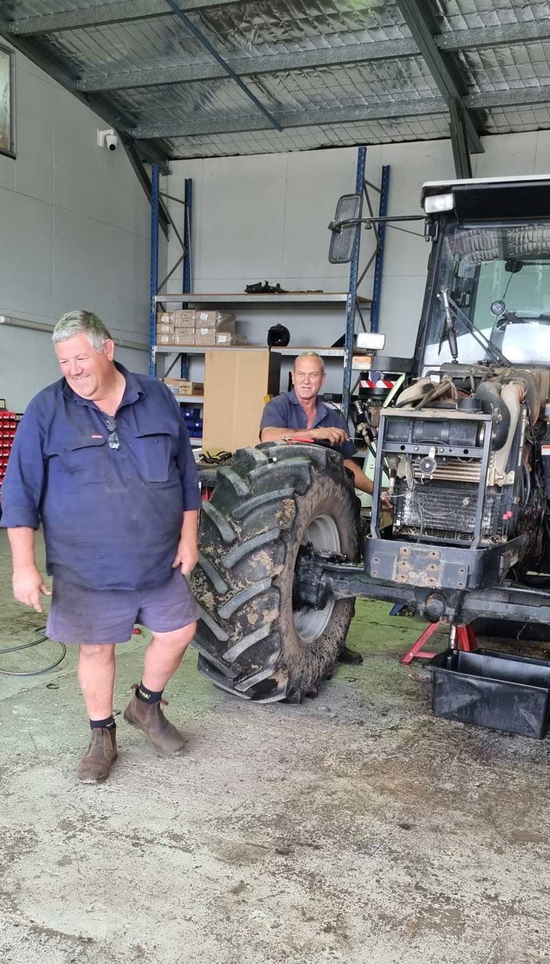 Two Men in Uniform Repairing the Tractor — Thompson's Farm Gear In Kempsey, NSW