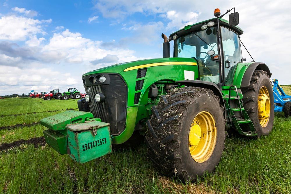 Green Tractor with Large Wheels in Rural Agricultural Setting — Thompson's Farm Gear In Wingham, NSW