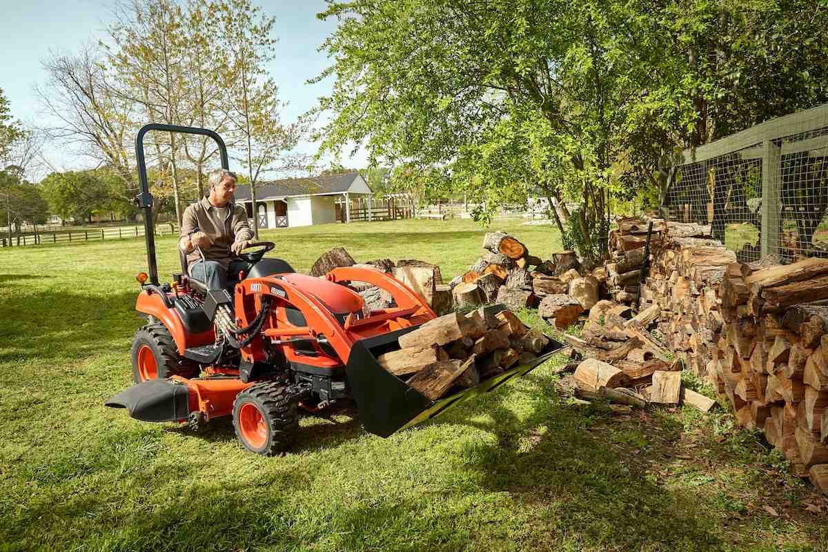 Person Operating An Orange Tractor To Move Logs — Thompson's Farm Gear In Wauchope, NSW