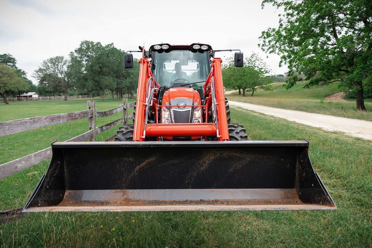 Orange Tractor With Front Loader Bucket On A Grassy Farm Path, Viewed Head-on — Thompson's Farm Gear In Wauchope, NSW