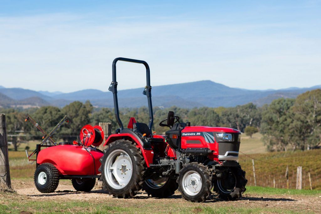 A Red and Black Tractor Is Plowing a Field — Thompson's Farm Gear In Wingham, NSW