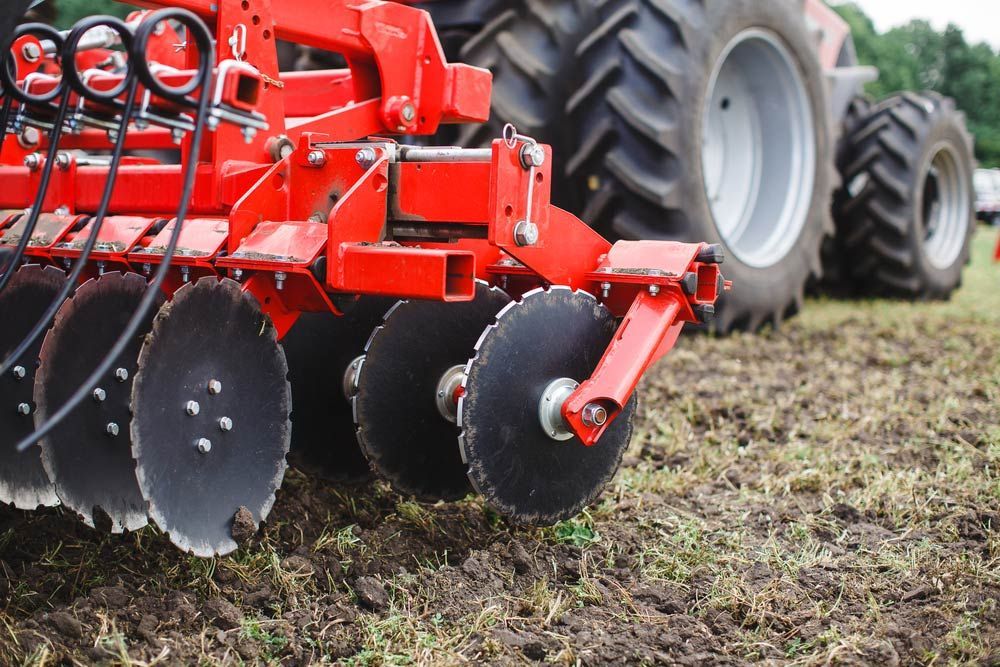 Red Tractor with Agricultural Plow in Action — Thompson's Farm Gear In Coffs Harbour, NSW
