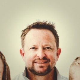 Smiling man with short hair and beard against a plain light background
