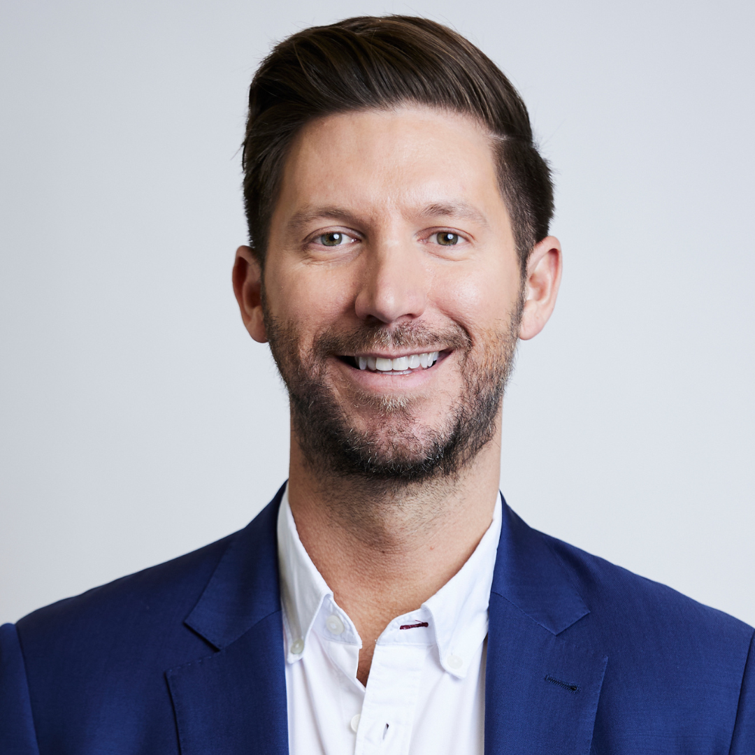 A man in a blue suit and white shirt is smiling for the camera.
