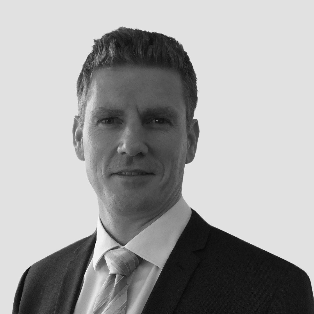 Formal portrait of a man in a dark suit and light tie against a plain background