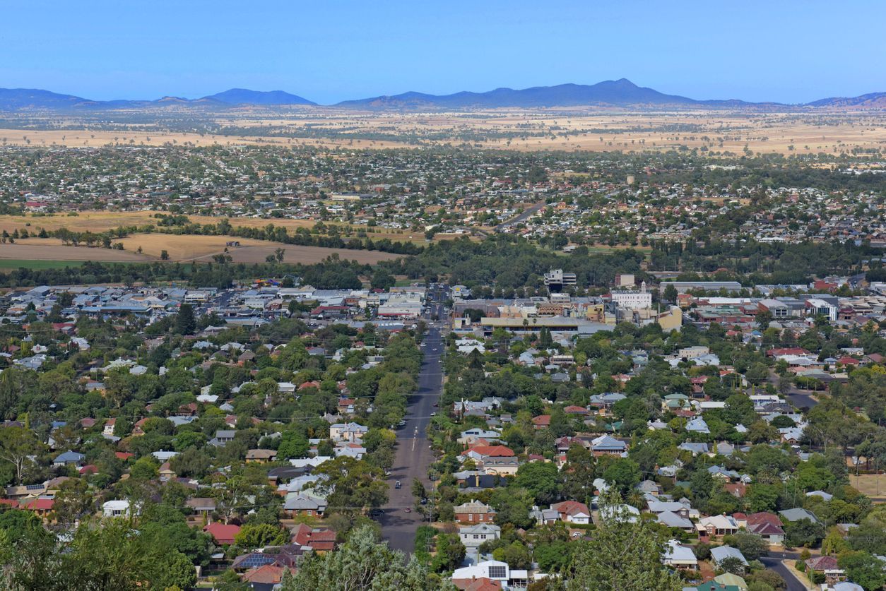 Aerial view of a leafy suburban neighborhood with distant mountains under a clear blue sky