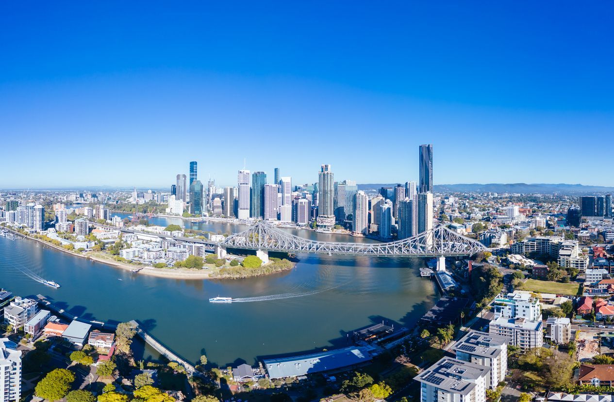 Aerial view of a city skyline beside a winding river under a clear blue sky