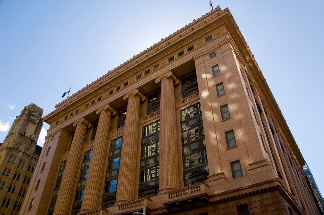 Tall historic stone building with columns viewed from below against a blue sky