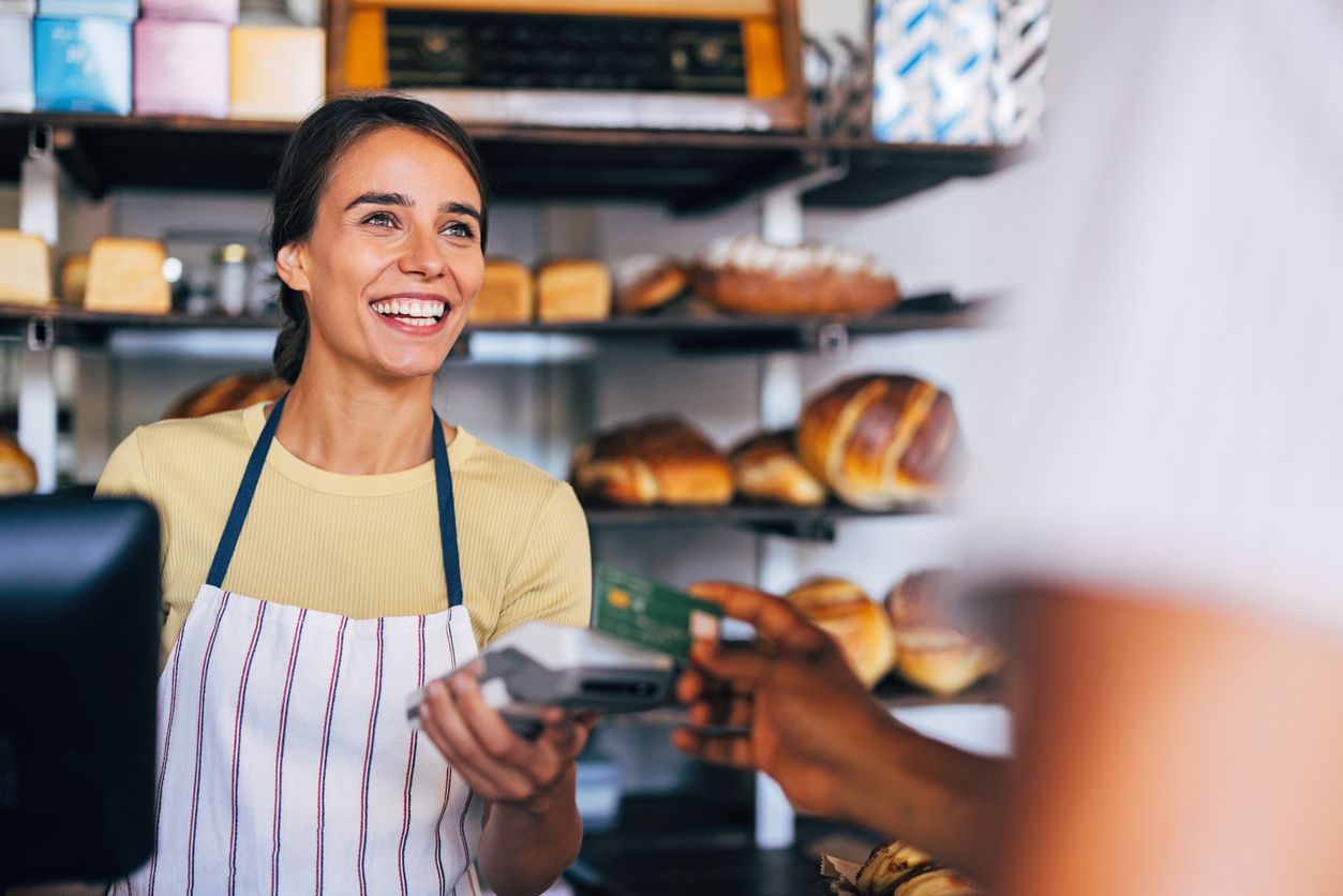 Smiling barista handing a coffee cup to a customer in a café