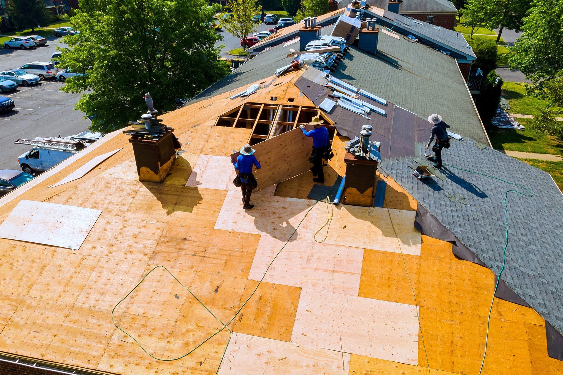 Workers installing roofing underlayment on a house roof with orange and gray sections