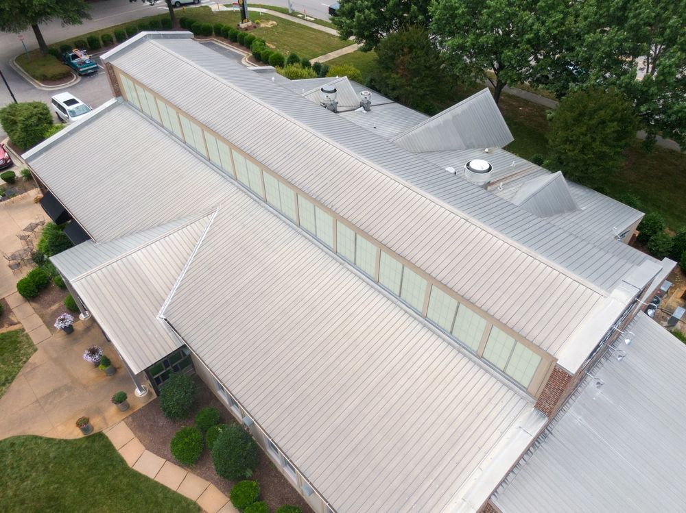 Aerial view of a light-roofed building surrounded by trees and walkways