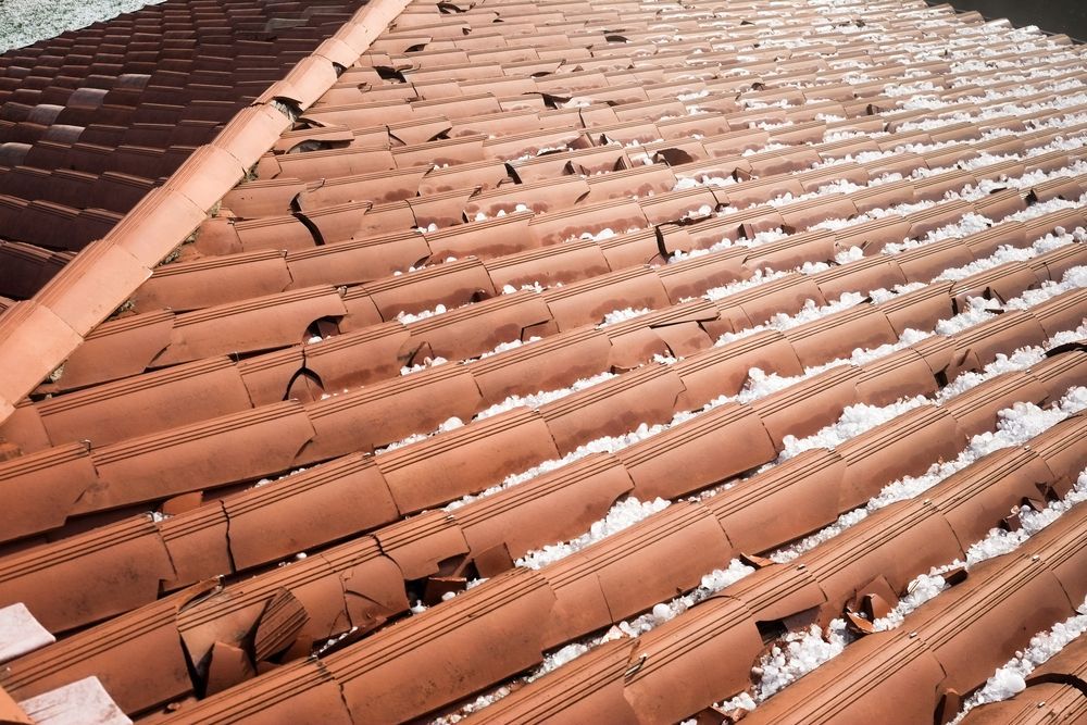 Terracotta roof tiles with multiple cracks and damage, viewed diagonally across the rooftop