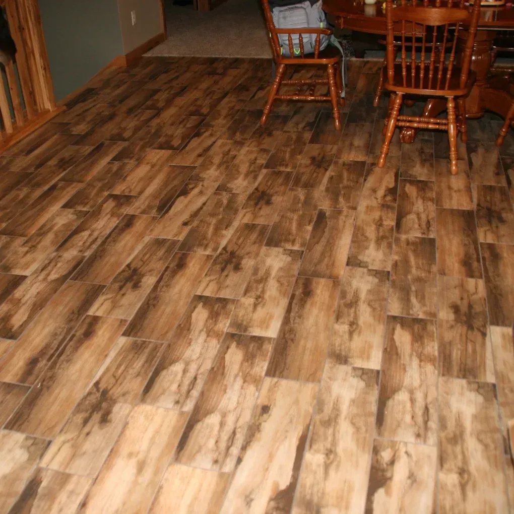 Wood-look laminate floor in a dining room with wooden chairs and table at the back.