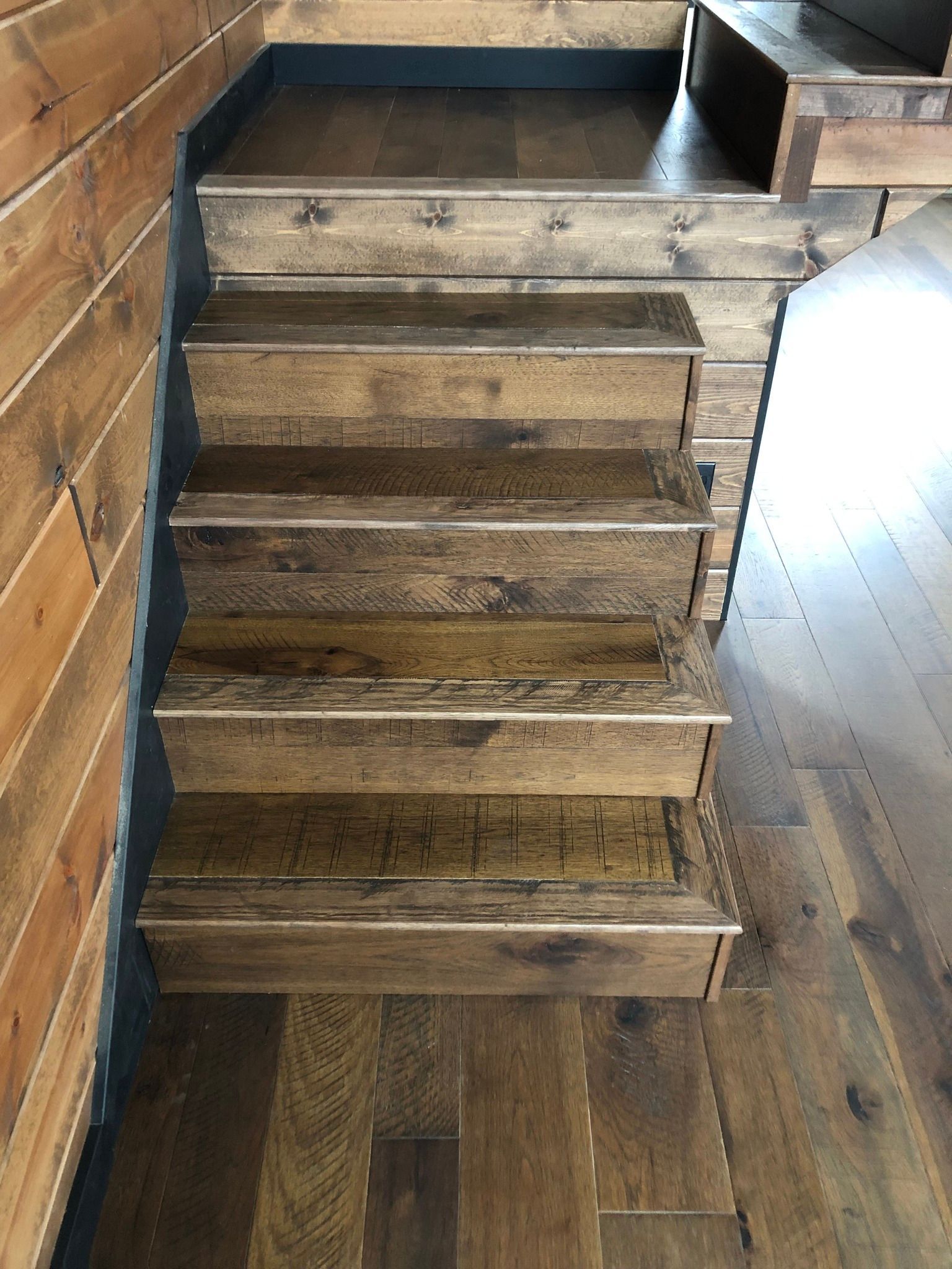 Wooden staircase with five steps and railings in a rustic interior with wood plank flooring