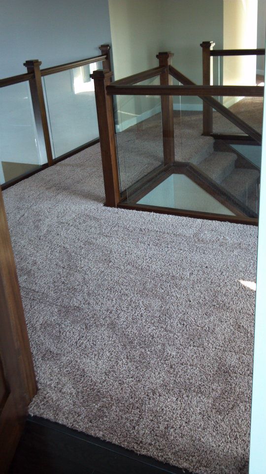 Carpeted upstairs landing with glass-and-wood railing around a stair opening.