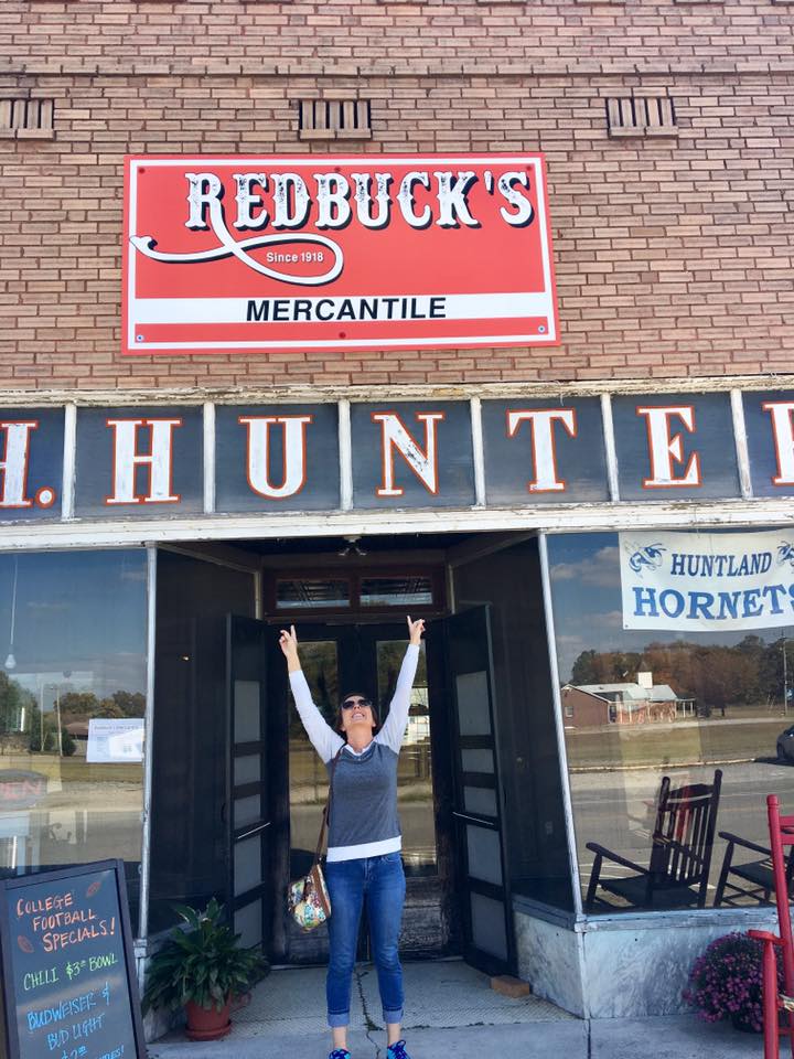 A woman is standing in front of a redbuck 's mercantile store