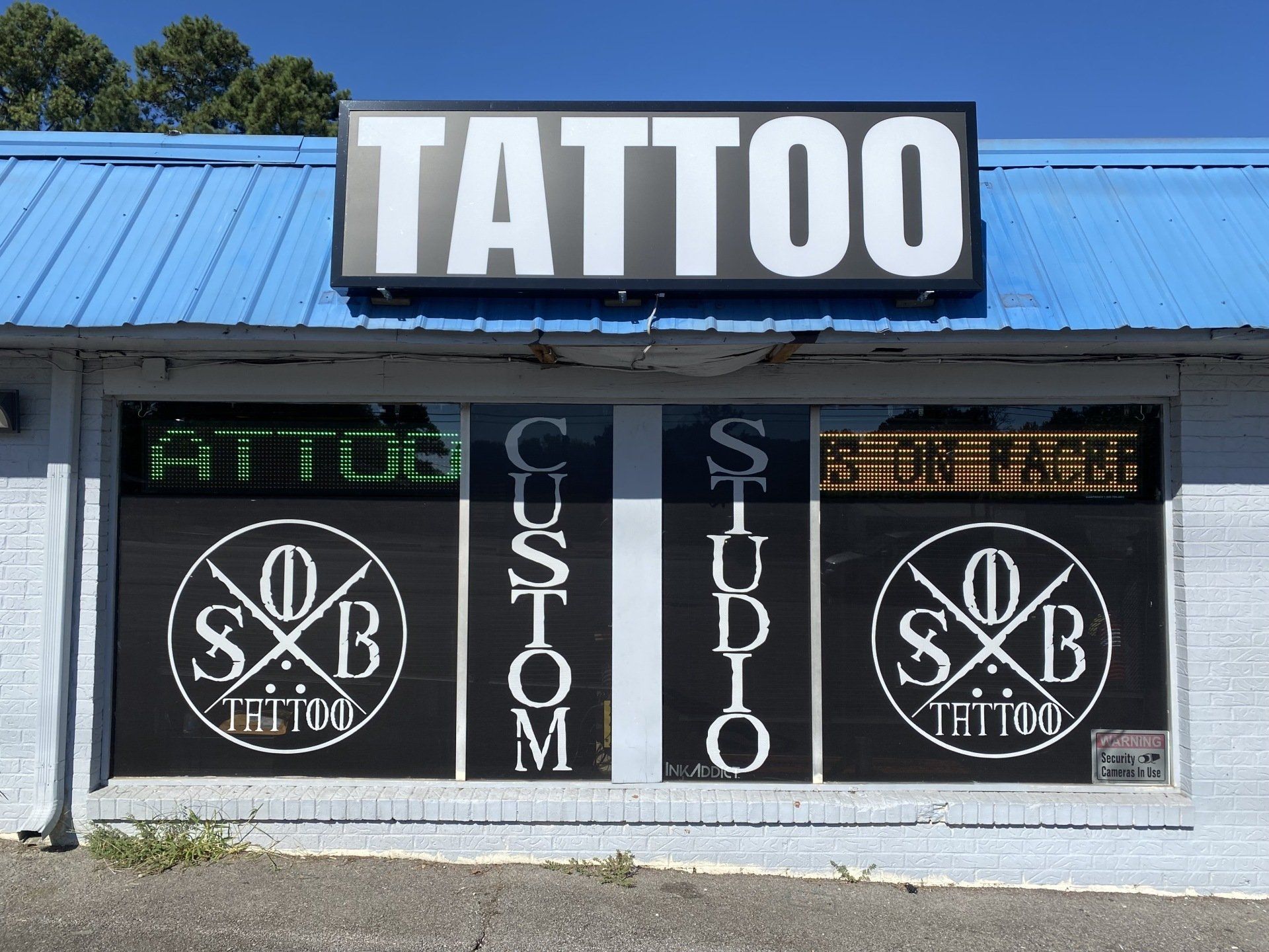 The front of a tattoo studio with a blue roof