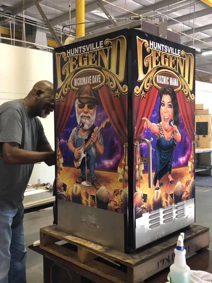 A man is working on a vending machine that says huntsville legend