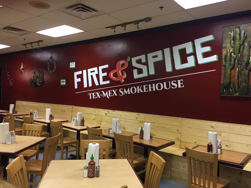 A restaurant with tables and chairs and a sign that says fire & spice