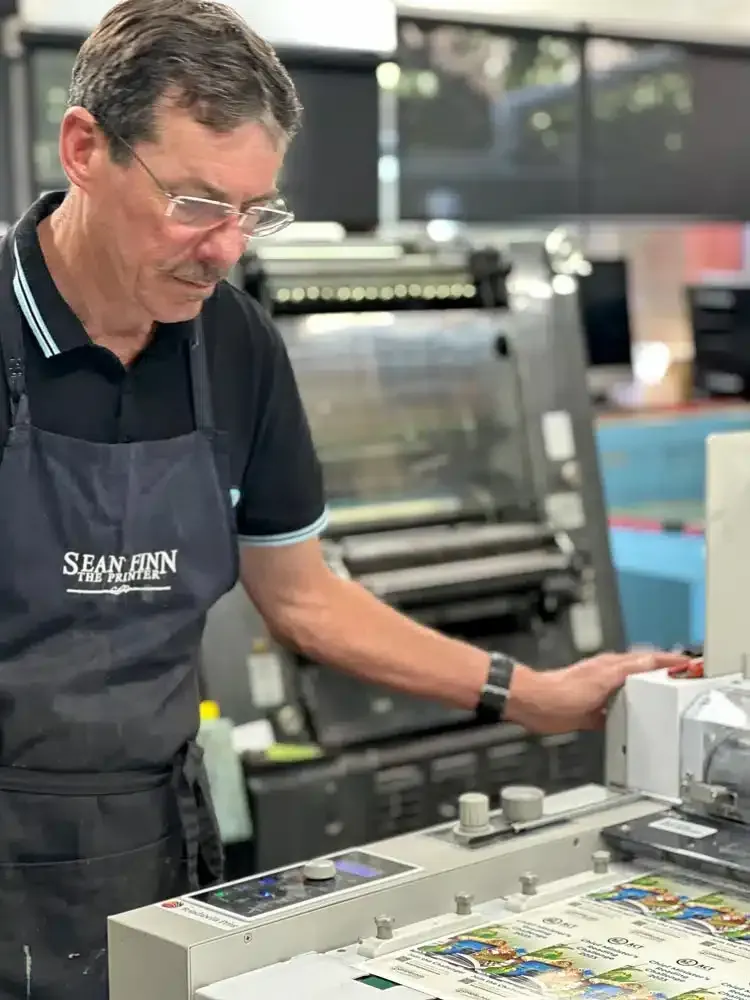 A Man in an Apron is Working on a Machine in a Factory — Brindabella Print In Gungahlin, ACT