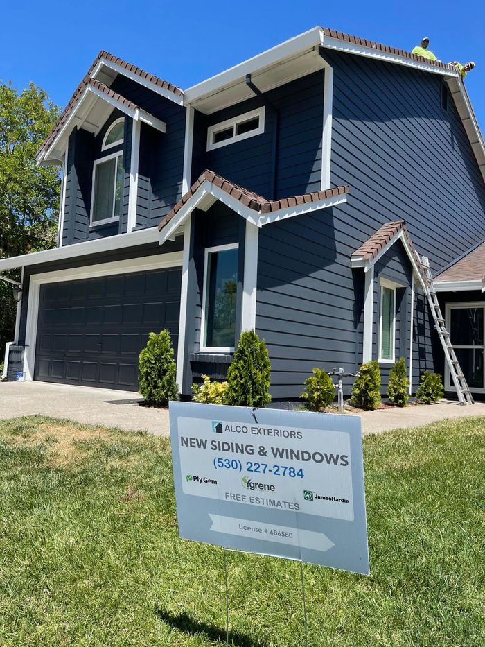 a house with a sign in front of it that says `` new siding & windows '' .