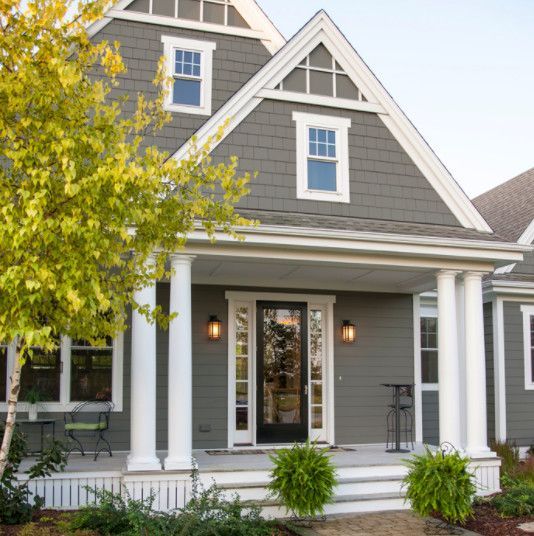 a gray house with white columns and a porch