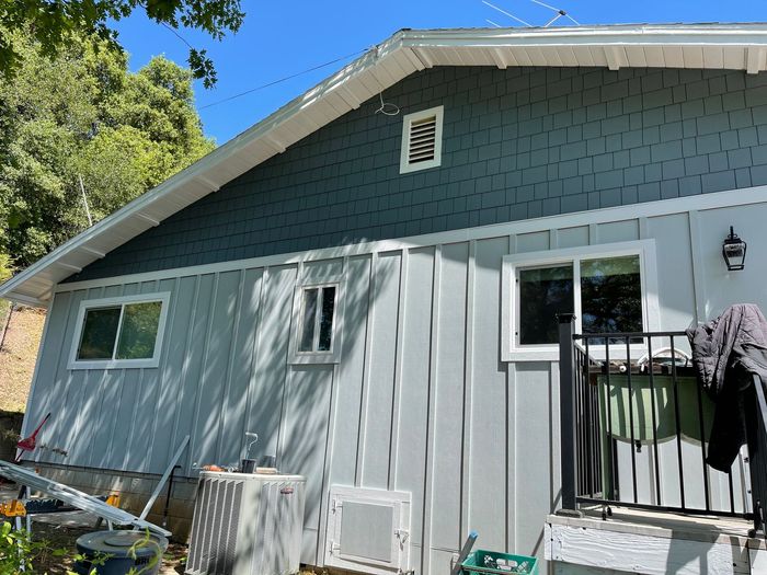 a house with a blue siding and white trim has a balcony .