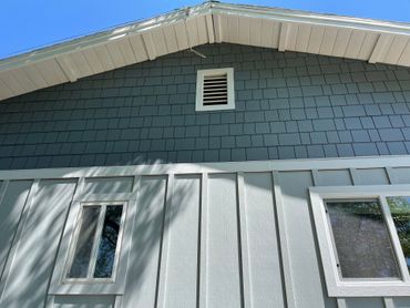 a gray house with a white roof and a window