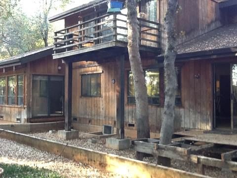 a wooden house with a balcony and trees in front of it