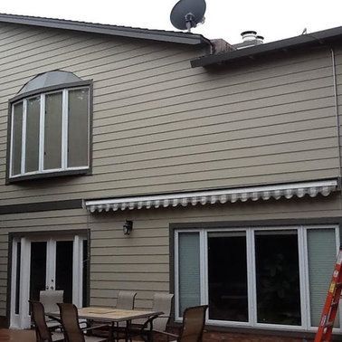 the back of a house with a table and chairs and a satellite dish on the roof. .