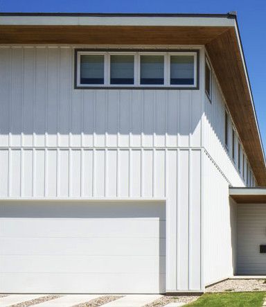 a white house with a white garage door and a blue sky in the background .