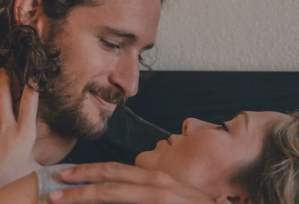 Couple sharing an intimate moment in a warm bedroom setting