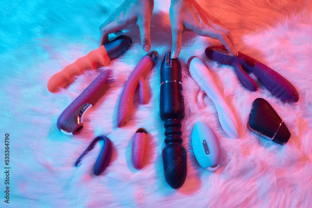 Red and black sex toys arranged on a pink fuzzy surface.